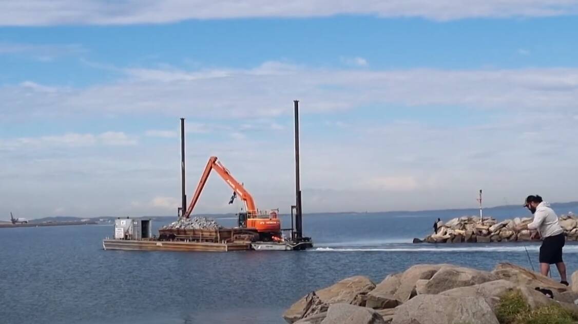 A barge takes rock to the reef site near the airport runways in mid-2023. Picture from video of Local Land Services NSW