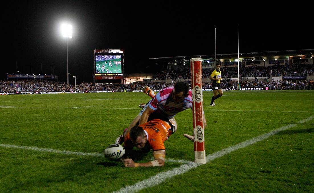 Pat Richards of the Tigers scores a try in the tackle of Jonathan Wright during the round 10 NRL match between the Cronulla-Sutherland Sharks and the Wests Tigers at Remondis Stadium. Picture: Renee McKay/Getty Images