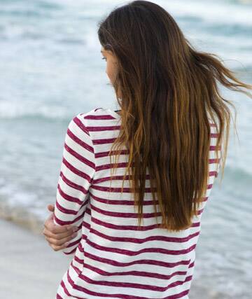 Young woman standing at beach, rear view Photo: PhotoAlto/Frederic Cirou