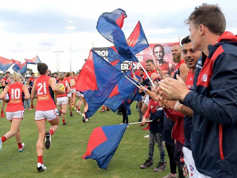 Melbourne's AFL players support their women's team before a match.