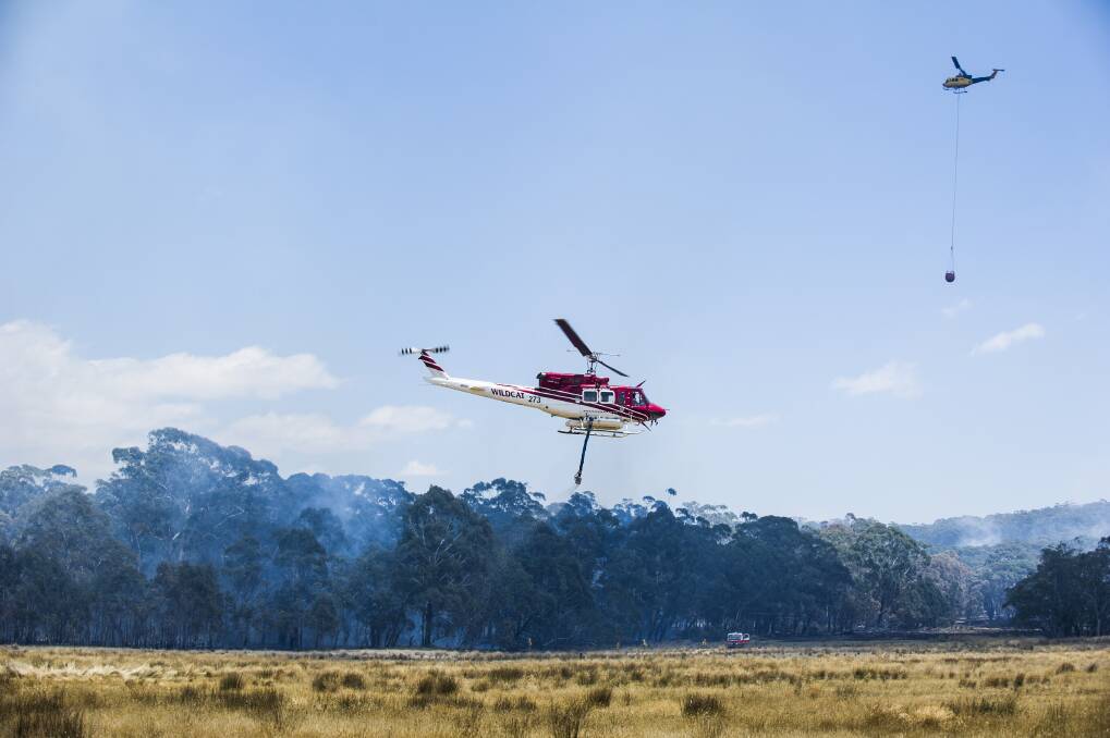 A water bombing helicopters work to control bushfire next to the Kings Highway near Bungendore. January 9, 2013. Photo: Rohan Thomson.